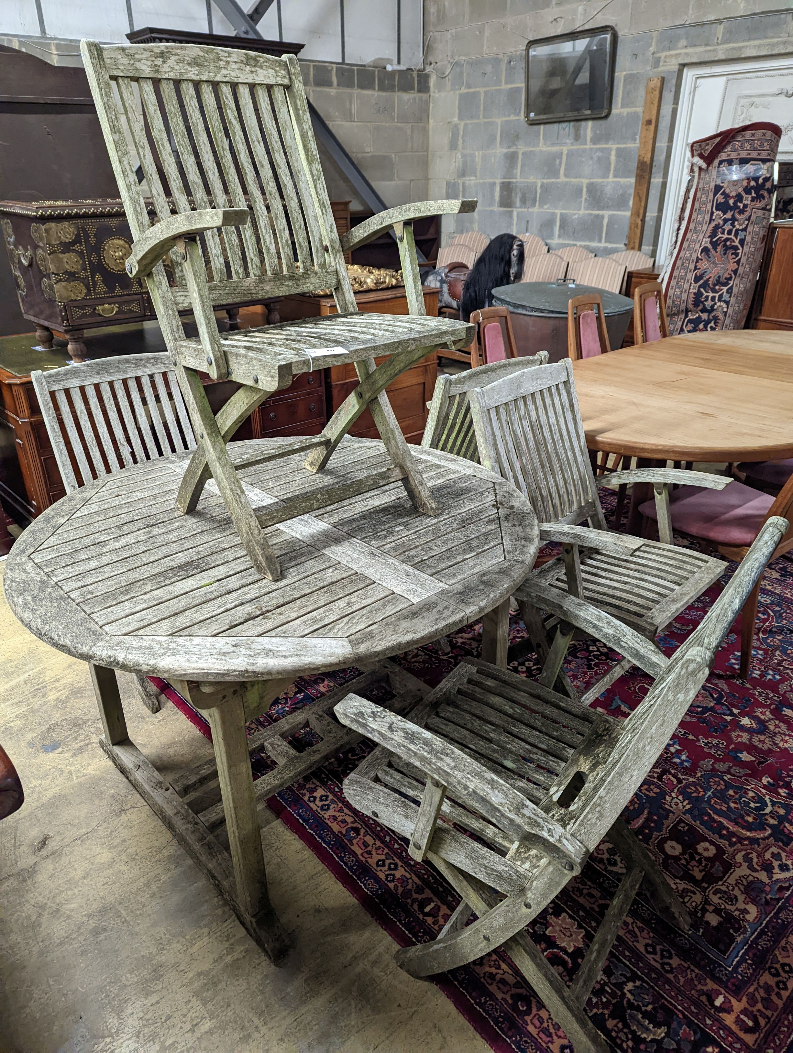 A weathered teak circular extending garden table, 120cm diameter, height 74cm together with five Lindsey teak folding garden elbow chairs